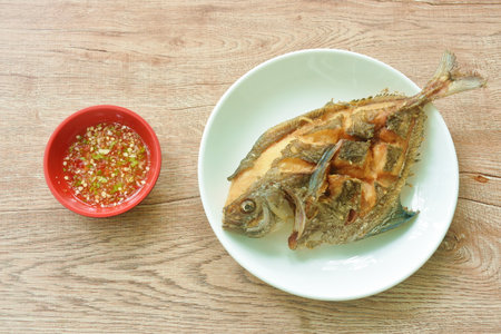 crispy fried black butterfish or silver pomfret; arranging on plate dipping spicy chili sauce in cupの写真素材