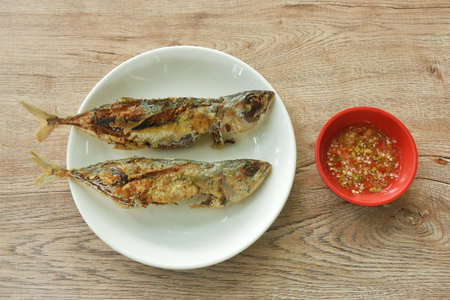 crispy fried fresh mackerel fish arranging on plate dipping spicy chili sauce in cup