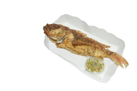 crispy fried fresh red snapper fish arranging on paper package dipping spicy chili sauce in white...