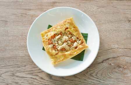 fried mashed pork with tomato and onion stuffed in Thai egg omelets on plate