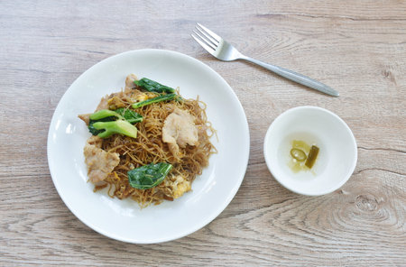 fried rice vermicelli noodles with slice soft marinated pork and Chinese kale in sweet black soybean sauce on plateの写真素材