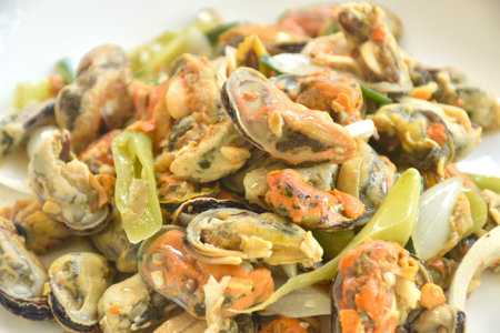 spicy stir fried mussel with slice onion and chili couple egg on plateの写真素材