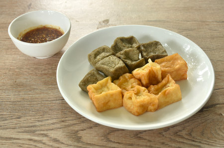 deep fried black and yellow tofu dipping with sweet crushed bean sauce on plateの写真素材