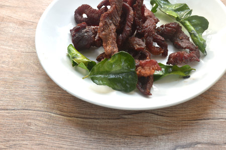 fried crispy salty fermenting beef meat with lemon leaf and chili on plateの写真素材