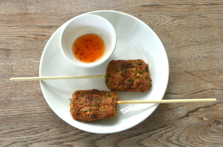 grilled fish patty on wooden stick on plate with sweet chili sauce