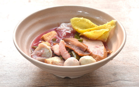 boiled fish ball with dumpling topping slice pickled squid and morning glory in red sauce soup on bowlの写真素材