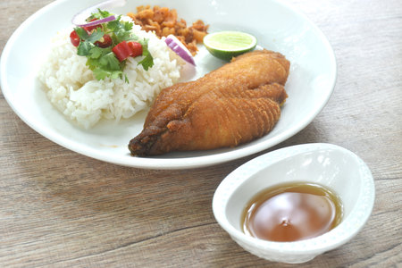 deep fried slice bass fish with rice topping chili and shallot dressing sweet fish sauce on plateの写真素材
