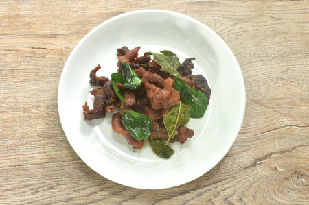 fried crispy salty fermenting pork meat with lemon leaf and chili on plateの写真素材