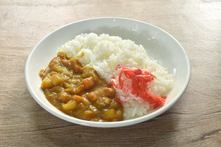 pork with potato and carrot in curry with rice topping slice red pickled cabbage on plateの写真素材