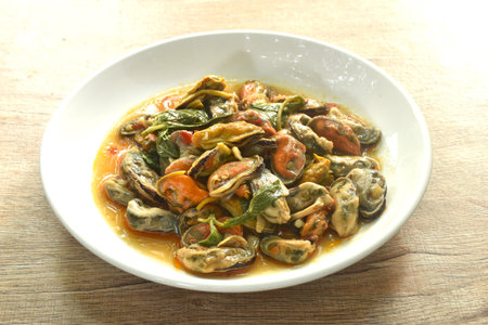 spicy stir fried mussel with chilin and basil leaf in curry sauce on plateの写真素材