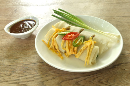 fresh Chinese spring roll made from flour wrapped tofu and pork with bean sprout dressing sweet red gravy sauce on plateの写真素材
