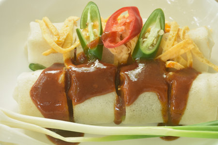 fresh Chinese spring roll made from flour wrapped tofu and pork with bean sprout dressing sweet red gravy sauce on plateの写真素材