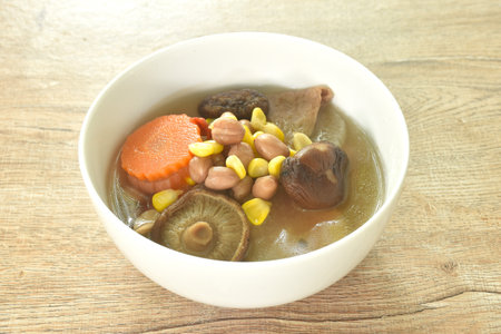 boiled corn with peanut and slice vegetable topping mushroom in Chinese herb soup on bowlの写真素材