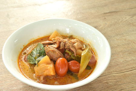 spicy boiled roasted duck meat with pineapple and tomato in coconut milk curry soup on bowlの写真素材