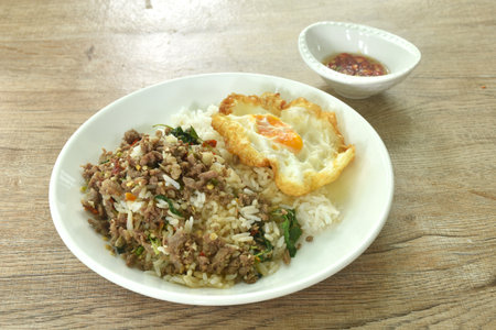 spicy stir fried chop beef meat with basil leaf and chili on rice topping egg in plateの写真素材