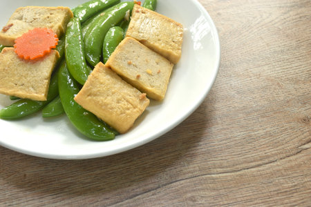 stir fried garden pea and carrot with slice tofu in soy sauce vegetarian food on dishの写真素材