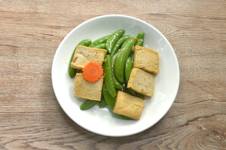 stir fried garden pea and carrot with slice tofu in soy sauce vegetarian foodの写真素材