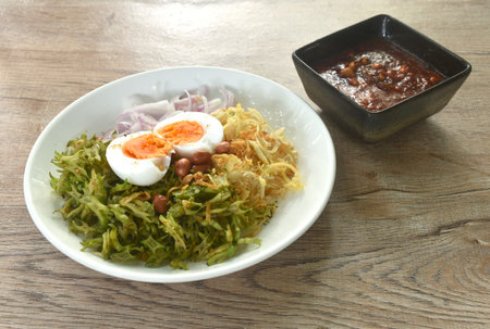 spicy and sour slice wing bean and banana blossom with chop pork sauce topping boiled egg Thai salad on plateの写真素材