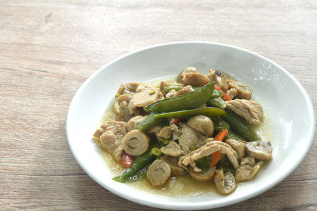 stir fried green pea and straw mushroom with pork in soybean sauce on plateの写真素材