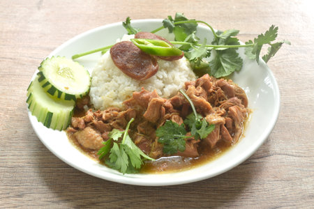 steamed chicken in salty gravy sauce dressing rice with chili and cucumber in plateの写真素材
