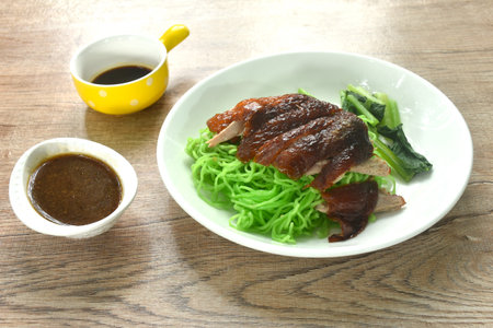 Chinese jade noodles topping roasted duck meat dipping sweet soy sauce on plateの写真素材