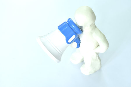 clay man model holding toy plastic white and blue megaphone and speaking on white backgroundの写真素材