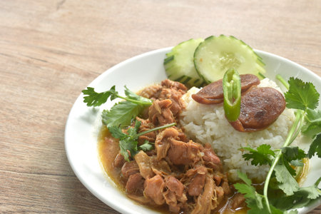 steamed chicken in salty gravy sauce dressing rice with chili and cucumber in plateの写真素材