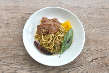 fried spaghetti topping crispy pork bacon and slice dry chili with bell pepper on plateの写真素材