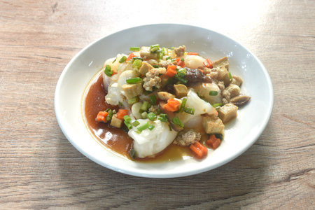 steamed large rice noodles topping chop pork and dice tofu with carrot dressing black soy sauce on plateの写真素材