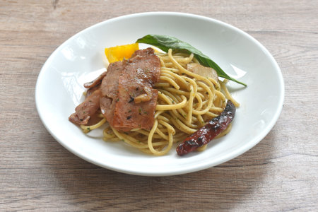 fried spaghetti topping crispy pork bacon and slice dry chili with bell pepper on plateの写真素材