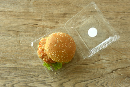 fried mashed shrimp hamburger and lettuce stuffed mayonnaise sauce with ketchup in plastic pakaging on tableの写真素材
