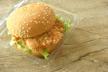 fried mashed shrimp hamburger and lettuce stuffed mayonnaise sauce with ketchup in plastic pakaging on tableの写真素材