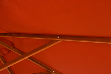 close up of red umbrella fabric with long wooden handle background and textureの写真素材