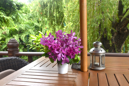 orchid decorating in flower pot and lantern on wooden table on terraceの写真素材