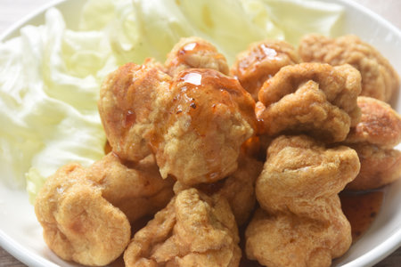 deep fried crispy fish ball dressing sweet chili tamarind sauce and slice cabbage on plateの写真素材