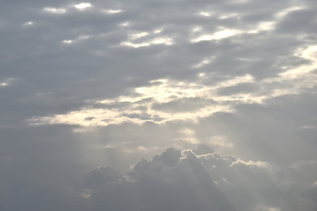 sun spreading light thourgh dark rain cloud floating on sky at sunset in eveningの写真素材