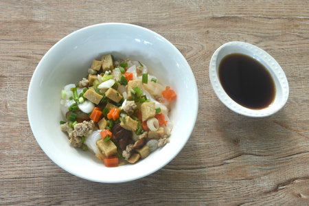 steamed large rice noodles topping chop pork and dice tofu with carrot dressing black soy sauce on plateの写真素材