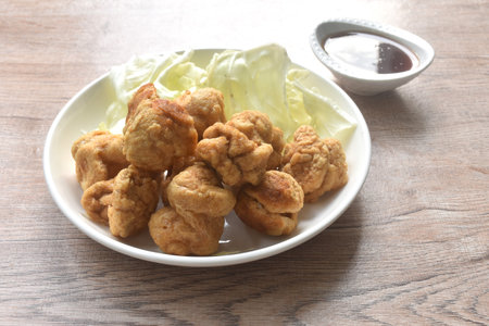 deep fried crispy fish ball dressing sweet chili tamarind sauce and slice cabbage on plateの写真素材