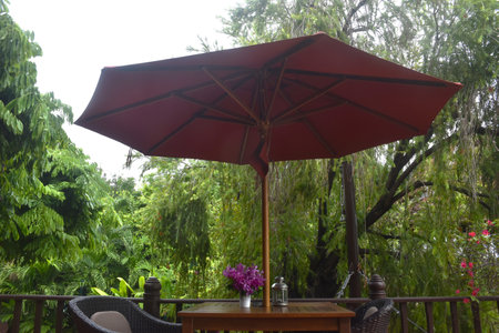 purple orchid decorating in flower pot and lantern on wooden table with red umbrella long handle on terraceの写真素材