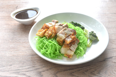 Chinese jade noodles topping roasted crispy pork dipping sweet soy sauce on plateの写真素材