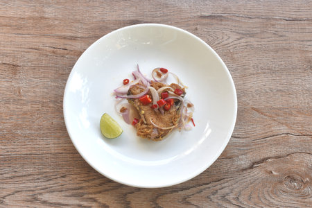 salty dry Indo-Pacific king mackerel fish topping chop shallot and chili with slice lemon salad on plateの写真素材