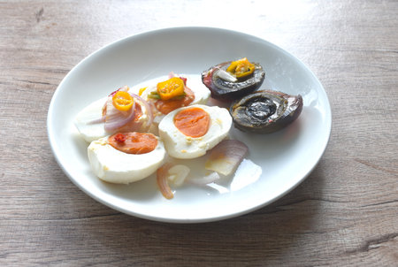 boiled salty and black preserved egg half cut with slice shallot and chili salad on plateの写真素材