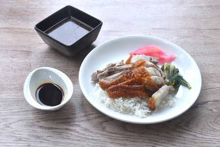 slice roasted duck couple crispy pork topping rice with pink pickled ginger and boiled cabbage dressing sweet soy sauce on plateの写真素材