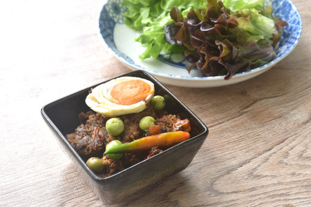 spicy fried chop pork Thai chili pasted topping salty egg in bowl eat couple fresh green oak vegetableの写真素材