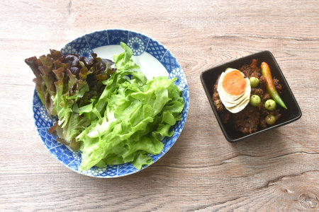 spicy fried chop pork Thai chili pasted topping salty egg in bowl eat couple fresh green oak vegetableの写真素材
