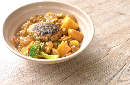 hamburg crispy fried chop pork with boiled vegetable topping plain rice dressing potato and carrot in Japanese curry on plateの写真素材