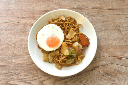 fried yakisoba Japanese noodles slice cabbage and carrot topping egg on plateの写真素材