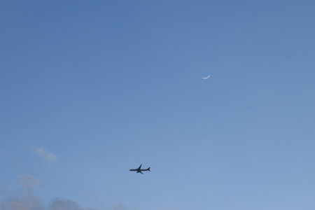 plane flyong pass moon and on twilight sky in eveningの写真素材