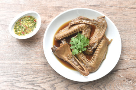 chop boiled duck wing and beak with tongue stew in brown soy soup on plate dipping spicy sour chili sauceの写真素材