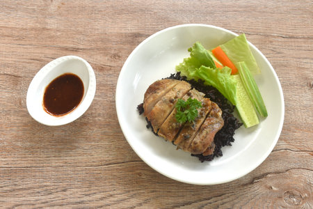 grilled slice chicken on black riceberry with cucumber carrot and lettuce on plate dipping Thai spicy tamarind sauceの写真素材